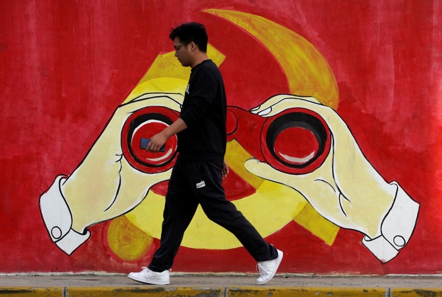 A man walks next to a mural showing an image of the Chinese Communist Party's emblem along a street in Shanghai, China September 25, 2019. REUTERS/Aly Song
