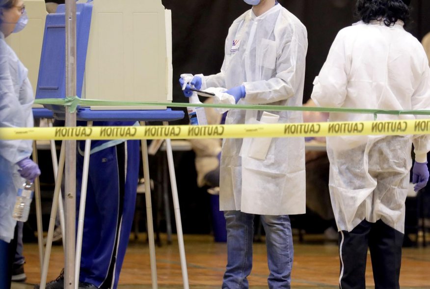 A poll worker wearing a mask to help slow the spread of coronavirus disease (COVID-19) sprays down a voting booth after use during the presidential primary election at Riverside High School in Milwaukee, Wisconsin, U.S. April 7, 2020. Mike De Sisti/Milwau