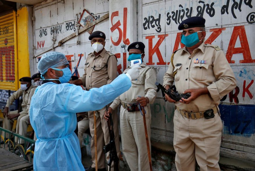 A paramedic uses an infrared thermometer to measure the temperature of a police officer alongside a road during a 21-day nationwide lockdown to slow the spreading of coronavirus disease (COVID-19) in Ahmedabad, India, April 9, 2020. REUTERS/Amit Dave