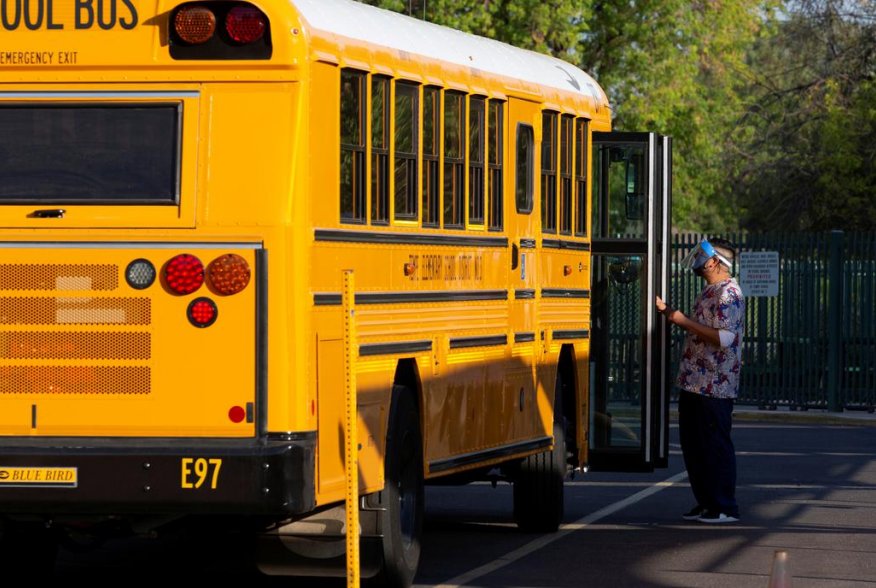 An employee waits to assist a student off a bus as in-person learning resumes with restrictions in place to prevent the spread of coronavirus disease (COVID-19) at Rover Elementary School in Tempe, Arizona, U.S., August 17, 2020. REUTERS/Cheney Orr