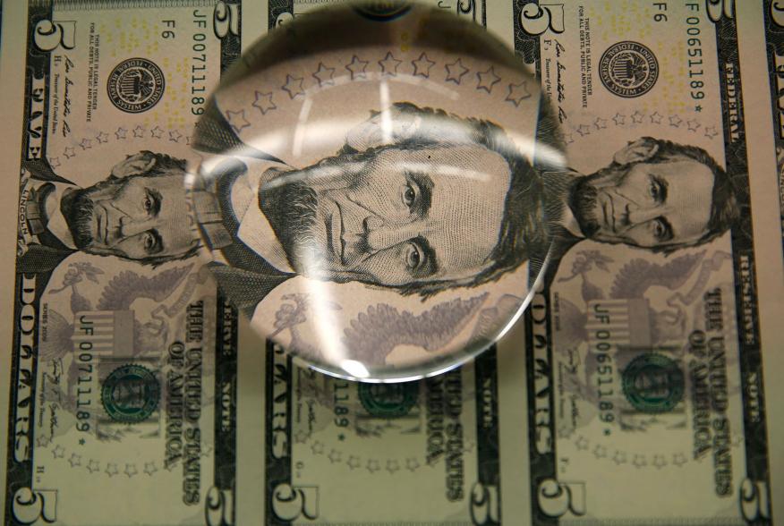 Sheets of former U.S. President Abraham Lincoln on the five-dollar bill currency are seen through a magnifying glass at the Bureau of Engraving and Printing in Washington March 26, 2015. The 150th anniversary of Lincoln's assassination at Ford's Theatre i