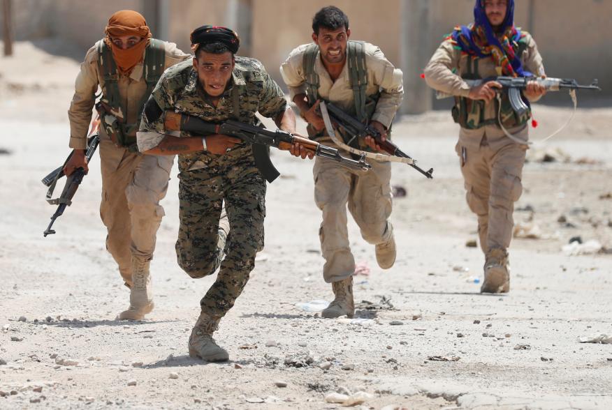 Kurdish fighters from the People's Protection Units (YPG) run across a street in Raqqa, Syria July 3, 2017. REUTERS/Goran Tomasevic