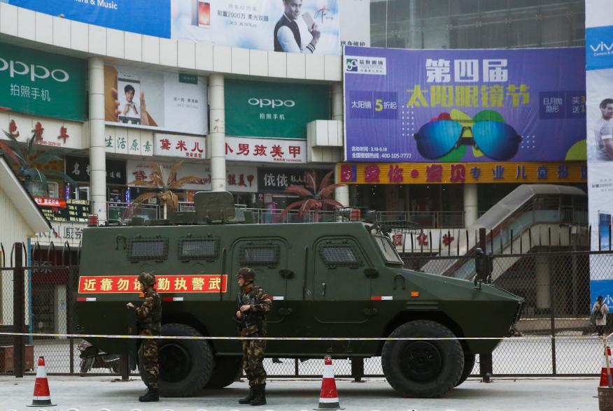 Security personel stand in front of an armoured vehicle in Kashgar, Xinjiang Uighur Autonomous Region, China, March 24, 2017. REUTERS/Thomas Peter