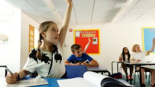 A girl gestures in a classroom at Watlington Primary School during the last day of school, amid the coronavirus disease (COVID-19) outbreak, in Watlington , Britain, July 17, 2020. REUTERS/Eddie Keogh