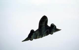 An underside view of an SR-71 Blackbird strategic reconnaissance aircraft in flight at an undisclosed location.