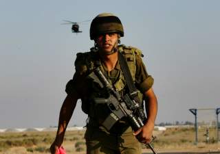 An Israeli soldier watches a chopper land on a military area in Kerem Shalom at the border with Gaza June 28, 2006. Israel fired artillery shells into the northern Gaza Strip on Wednesday as troops and tanks prepared to widen an offensive aimed at forcing