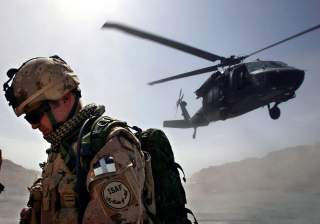 A Canadian soldier from the NATO-led coalition force turns his back away from a dust cloud kicked up by a Blackhawk helicopter taking off from the forward operating base of Ma'sum Ghar, Afghanistan, July 1, 2007. REUTERS/ Finbarr O'Reilly (AFGHANISTAN)