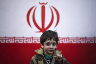 A young boy stands in front of Iran's national flag with his ink stained face and finger, symbolizing a voter who already has cast his vote, in a polling station during Iran's parliamentary election in southern Tehran March 2, 2012. REUTERS/Morteza Nikoub