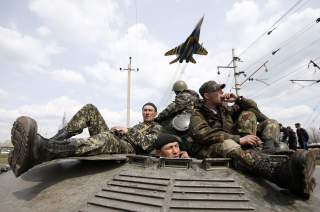 A fighter jet flies above as Ukrainian soldiers sit on an armoured personnel carrier in Kramatorsk, in eastern Ukraine April 16, 2014. Ukrainian government forces and separatist pro-Russian militia staged rival shows of force in eastern Ukraine on Wednesd