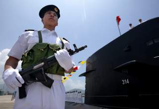 A Chinese Naval officer stands guard beside a submarine at the Ngong Shuen Chau Naval Base in Hong Kong April 30, 2004. China will expand the membership of the military's top decision-making body to 