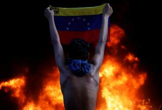 A protester holds a national flag as a bank branch, housed in the magistracy of the Supreme Court of Justice, burns during a rally against Venezuela's President Nicolas Maduro, in Caracas, Venezuela June 12, 2017. REUTERS/Carlos Garcia Rawlins TPX IMAGES 