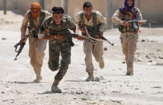 Kurdish fighters from the People's Protection Units (YPG) run across a street in Raqqa, Syria July 3, 2017. REUTERS/Goran Tomasevic