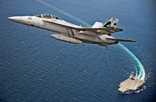 An F/A-18F Super Hornet jet flies over the USS Gerald R. Ford as the U.S. Navy aircraft carrier tests its EMALS magnetic launching system, which replaces the steam catapult, and new AAG arrested landing system in the Atlantic Ocean July 28, 2017. Picture 