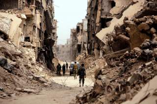 FILE PHOTO: Soldiers walk past damaged buildings in the Yarmouk Palestinian camp in Damascus, Syria May 22, 2018. REUTERS/Omar Sanadiki - RC18889192B0/File Photo