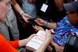 Democratic 2020 U.S. presidential candidate and U.S. Senator Elizabeth Warren (D-MA) autographs a copy of The Mueller Report with 