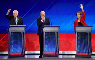 Former Vice President Joe Biden stands between Senator Bernie Sanders (L) and Senator Elizabeth Warren (R) as they both raise their hands to answer a question at the 2020 Democratic U.S. presidential debate in Houston, Texas, U.S. September 12, 2019.