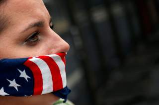 A supporter of U.S. Senator Bernie Sanders covers her mouth with a bandana in the colors of the American flag while standing along the perimeter fence of the 2016 Democratic National Convention in Philadelphia, Pennsylvania on July 28, 2016. REUTERS/Adree