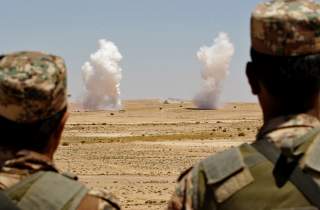 Jordanian soldiers watch smoke rising during an artillery drill, part of the 