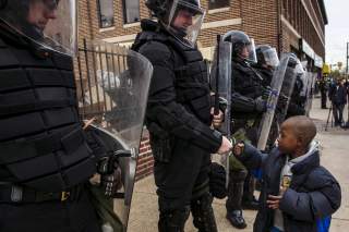 A young boy greets police officers in riot gear during a march in Baltimore, Maryland May 1, 2015 following the decision to charge six Baltimore police officers -- including one with murder -- in the death of Freddie Gray, a black man who was arrested and