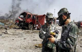 Soldiers of the People's Liberation Army anti-chemical warfare corps work next to a damaged firefighting vehicle at the site of Wednesday night's explosions at Binhai new district in Tianjin, China, August 16, 2015.