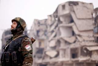 A member of forces loyal to Syria's President Bashar al-Assad stands near damaged buildings in Aleppo's Salaheddine district, Syria December 16, 2016. REUTERS/Omar Sanadiki