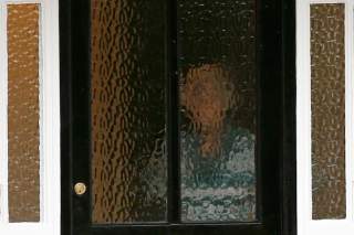 A person stands behind textured glass at an address which has been linked by local media to former British intelligence officer Christopher Steele, who has been named as the author of an intelligence dossier on President-elect Donald Trump.