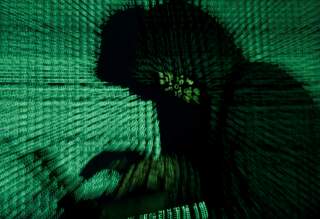 A man holds a laptop computer as cyber code is projected on him in this illustration picture taken on May 13, 2017. REUTERS/Kacper Pempel