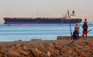 People walk on the beach as a container ship crosses the Gulf of Suez towards the Red Sea before entering the Suez Canal, in El Ain El Sokhna in Suez, east of Cairo, Egypt April 24, 2017. Picture taken April 24, 2017. REUTERS/Amr Abdallah Dalsh