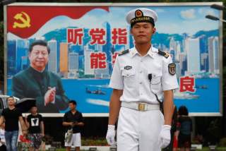 A People's Liberation Army Navy soldier stands in front of a backdrop featuring Chinese President Xi Jinping at a naval base in Hong Kong, China July 8, 2017. REUTERS/Bobby Yip