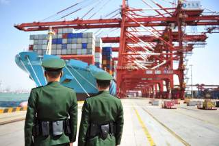 Police officers are seen in front of a cargo ship with containers at a port in Qingdao, Shandong province, China April 6, 2018. REUTERS/Stringer