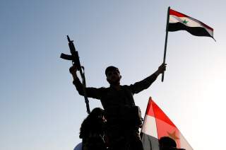 A Syrian soldier waves a flag during a protest against air strikes in Damascus,Syria April 14,2018.REUTERS/ Omar Sanadiki