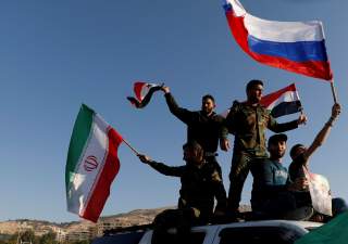 Syrians wave Iranian, Russian and Syrian flags during a protest against U.S.-led air strikes in Damascus,Syria April 14,2018.REUTERS/ Omar Sanadiki TPX IMAGES OF THE DAY