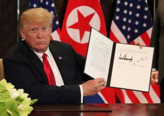 U.S. President Donald Trump shows the document, that he and North Korea's leader Kim Jong Un signed acknowledging the progress of the talks and pledge to keep momentum going, after their summit at the Capella Hotel on Sentosa island in Singapore June 12, 