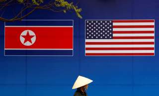 A person walks past a banner showing North Korean and U.S. flags ahead of the North Korea-U.S. summit in Hanoi, Vietnam, February 25, 2019. REUTERS/Kim Kyung-Hoon TPX IMAGES OF THE DAY