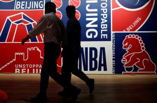 Men walk past a poster at an NBA exhibition in Beijing, China October 8, 2019. REUTERS/Jason Lee/File Photo