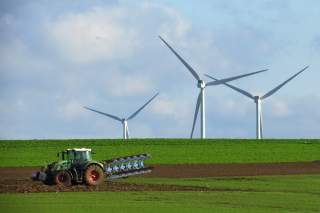 A French farmer drives a tractor as he ploughs a field in front of power-generating windmill turbines on a wind park in Havrincourt, France, November 10, 2019. Picture taken November 10, 2019. REUTERS/Pascal Rossignol