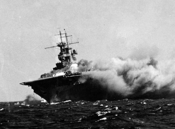  A port bow view of the ship shows her aflame and listing to starboard, 15 September 1942. Men on the flight deck desperately battle the spreading inferno. 