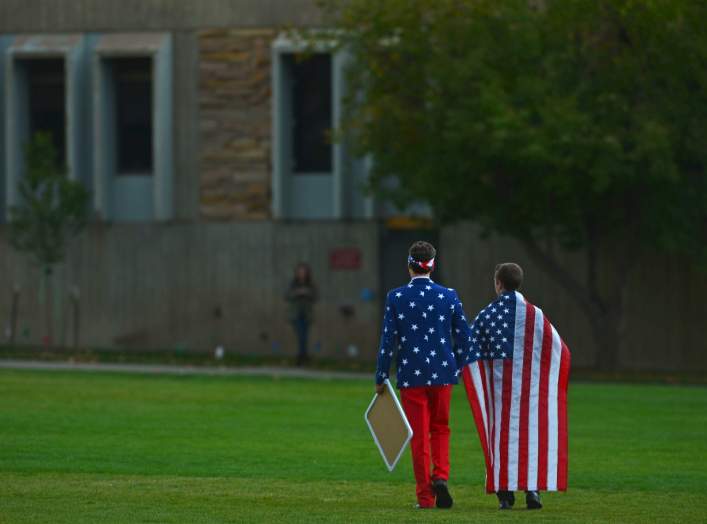 People wear the American flag as students and protesters gather at the "Free Speech Zone" located at the University of Colorado's Business Field, while candidates gather across the street for a forum held by CNBC, before the U.S. Republican presidential c