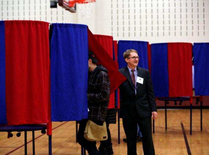 Election official Bill McClure assists voters at a polling place in Portsmouth, New Hampshire, U.S., November 6, 2018. REUTERS/Elizabeth Frantz