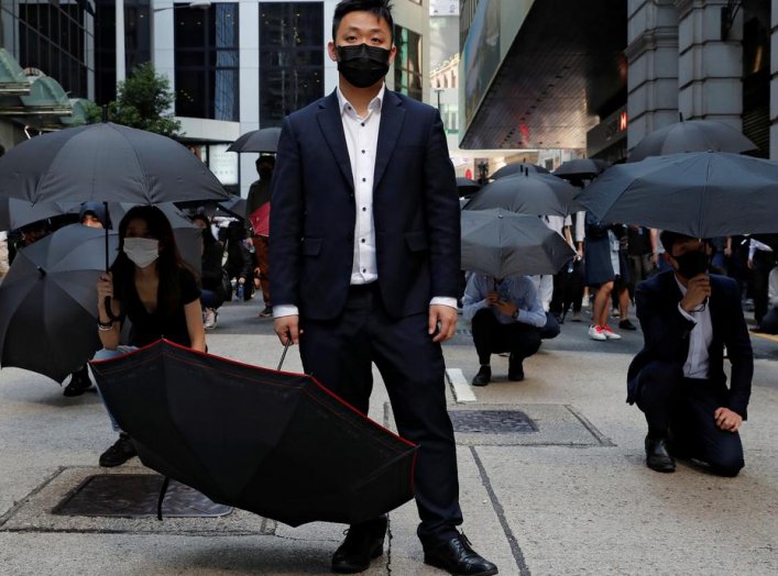 Office workers hold umbrellas as they attend a flash mob anti-government protest after police fired tear gas at the financial Central district in Hong Kong, China, November 11, 2019. REUTERS/Tyrone Siu