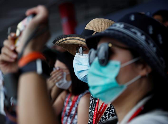 Spectators wearing masks in precaution of the coronavirus outbreak watch an aerial display at the Singapore Airshow in Singapore February 11, 2020. REUTERS/Edgar Su