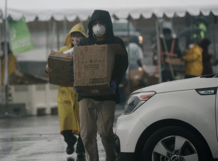 San Diego Food Bank volunteers carry boxes of leftover food after an emergency drive-through food and toilet paper distribution hosted at Southwestern College near the U.S.-Mexico border, amid the coronavirus disease (COVID-19) outbreak in Chula Vista, Ca