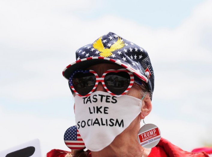 A woman wears a mask reading "Tastes Like Socialism" at a protest against restrictions implemented in response to the coronavirus disease (COVID-19) outbreak near Massachusetts Governor Charlie Baker’s house in Swampscott, Massachusetts, U.S., May 16, 202