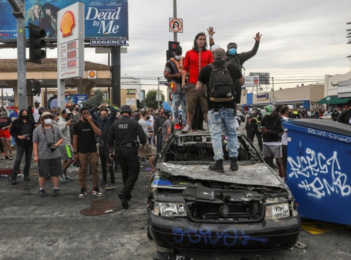 Demonstrators stand on top of a burned out police car during a protest against the death in Minneapolis police custody of George Floyd, in Los Angeles, California, U.S., May 30, 2020. REUTERS/Patrick T. Fallon