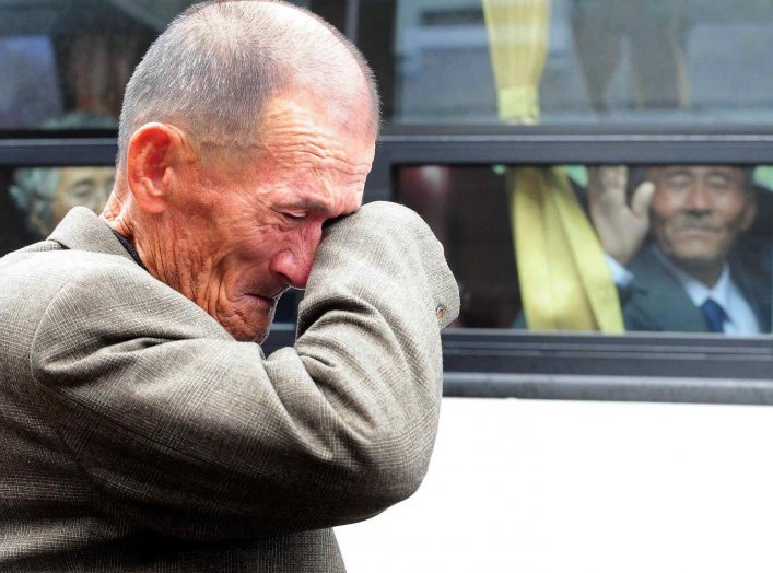 A North Korean man (R) on a bus waves his hand as a South Korean man weeps after a luncheon meeting during inter-Korean temporary family reunions at Mount Kumgang resort October 31, 2010. Kim Ho-Young/Korea Pool via REUTERS