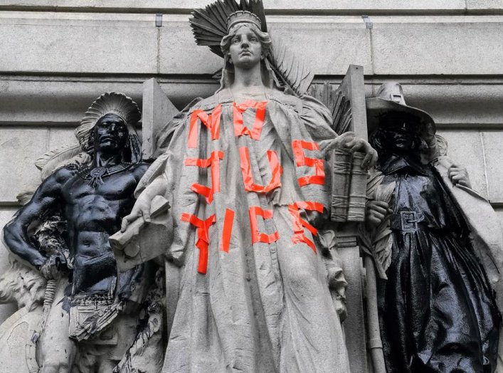 A defaced statue is pictured across from a protest to defund the police in a place they are calling the "City Hall Autonomous Zone" in support of "Black Lives Matter" in the Manhattan borough of New York City, New York, U.S., June 30, 2020. REUTERS/Carlo 