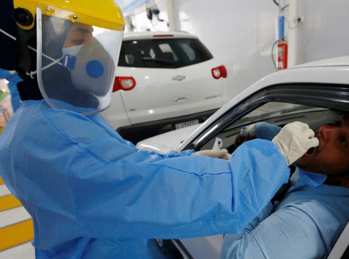 A medical team member wearing a protective suit takes a swab sample from a man at his car to test for the coronavirus disease (COVID-19) at the coronavirus testing center, in the holy city of Najaf, Iraq July 12, 2020. Picture taken July 12, 2020. REUTERS