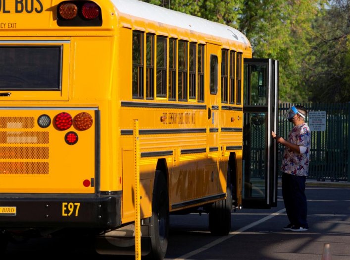 An employee waits to assist a student off a bus as in-person learning resumes with restrictions in place to prevent the spread of coronavirus disease (COVID-19) at Rover Elementary School in Tempe, Arizona, U.S., August 17, 2020. REUTERS/Cheney Orr