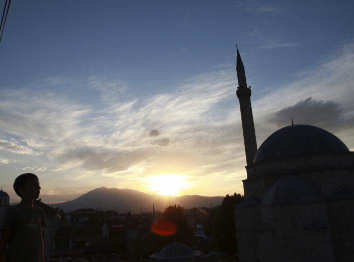 Image: A boy looks at the sky near an orthodox church and a mosque in Prizren, southwest from capital Pristina August 20, 2014. REUTERS/Hazir Reka 