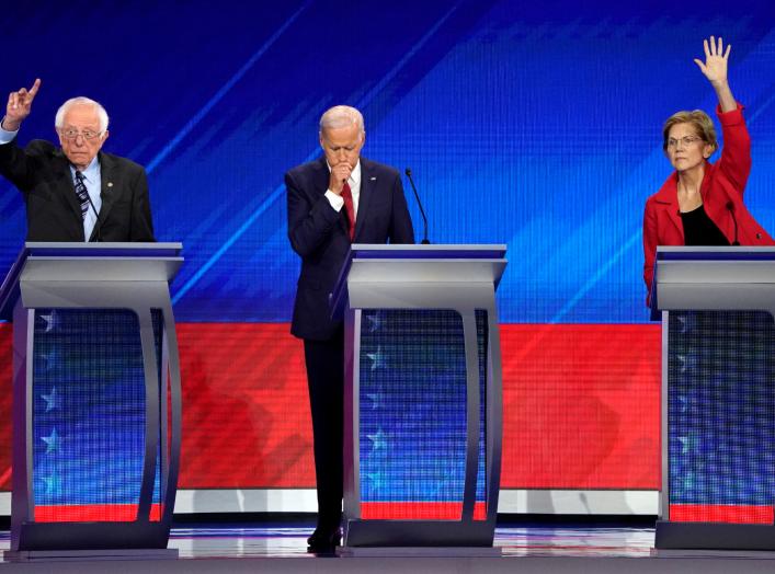 Former Vice President Joe Biden stands between Senator Bernie Sanders (L) and Senator Elizabeth Warren (R) as they both raise their hands to answer a question at the 2020 Democratic U.S. presidential debate in Houston, Texas, U.S. September 12, 2019.